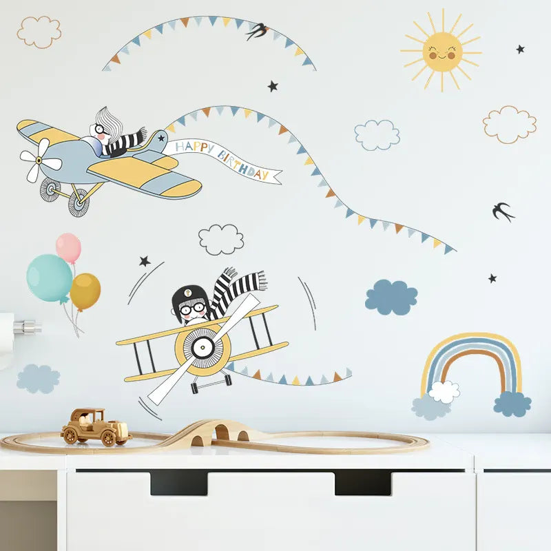 Children's wall decal with airplanes, balloons, and rainbow on a white wall.