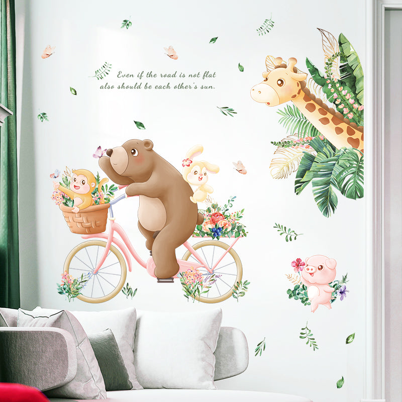 Wall decal with bear on a bicycle, flowers, and animals on a white wall.
