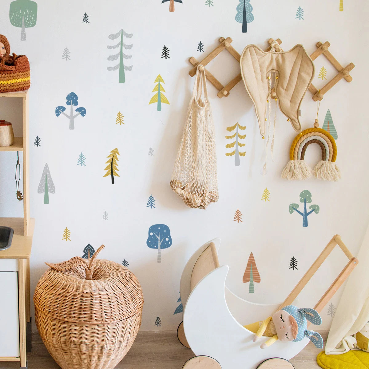 Children's room with wooden toys, a basket, and wall decorations with tree patterns.