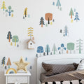 Children's room with forest-themed wall decals and a bed with polka dot pillows.