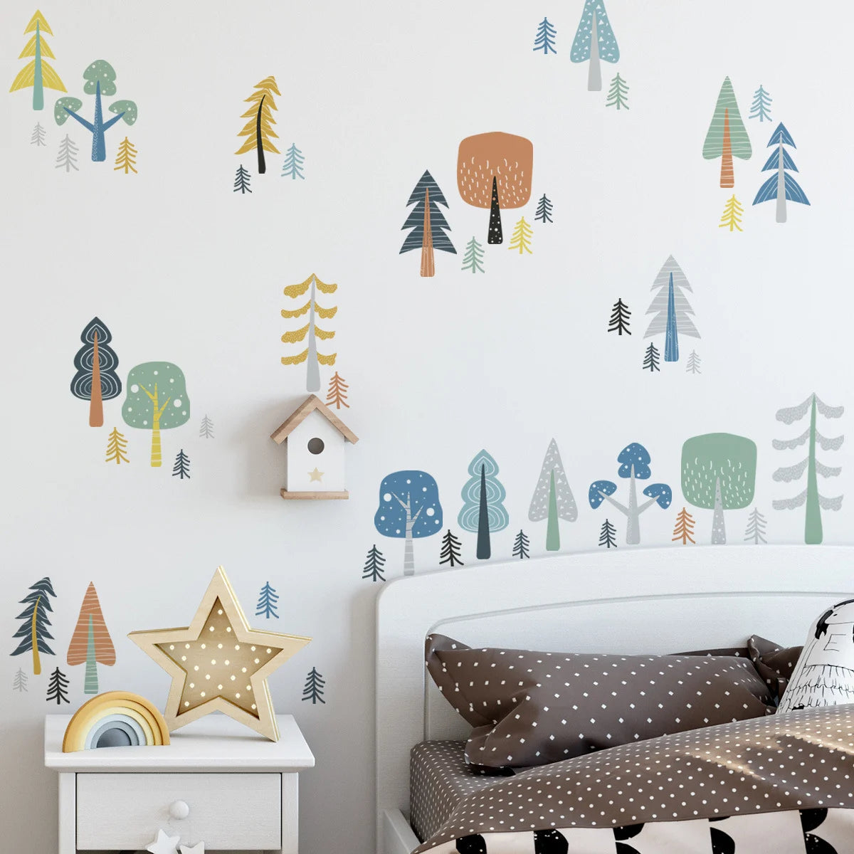 Children's room with forest-themed wall decals and a bed with polka dot pillows.