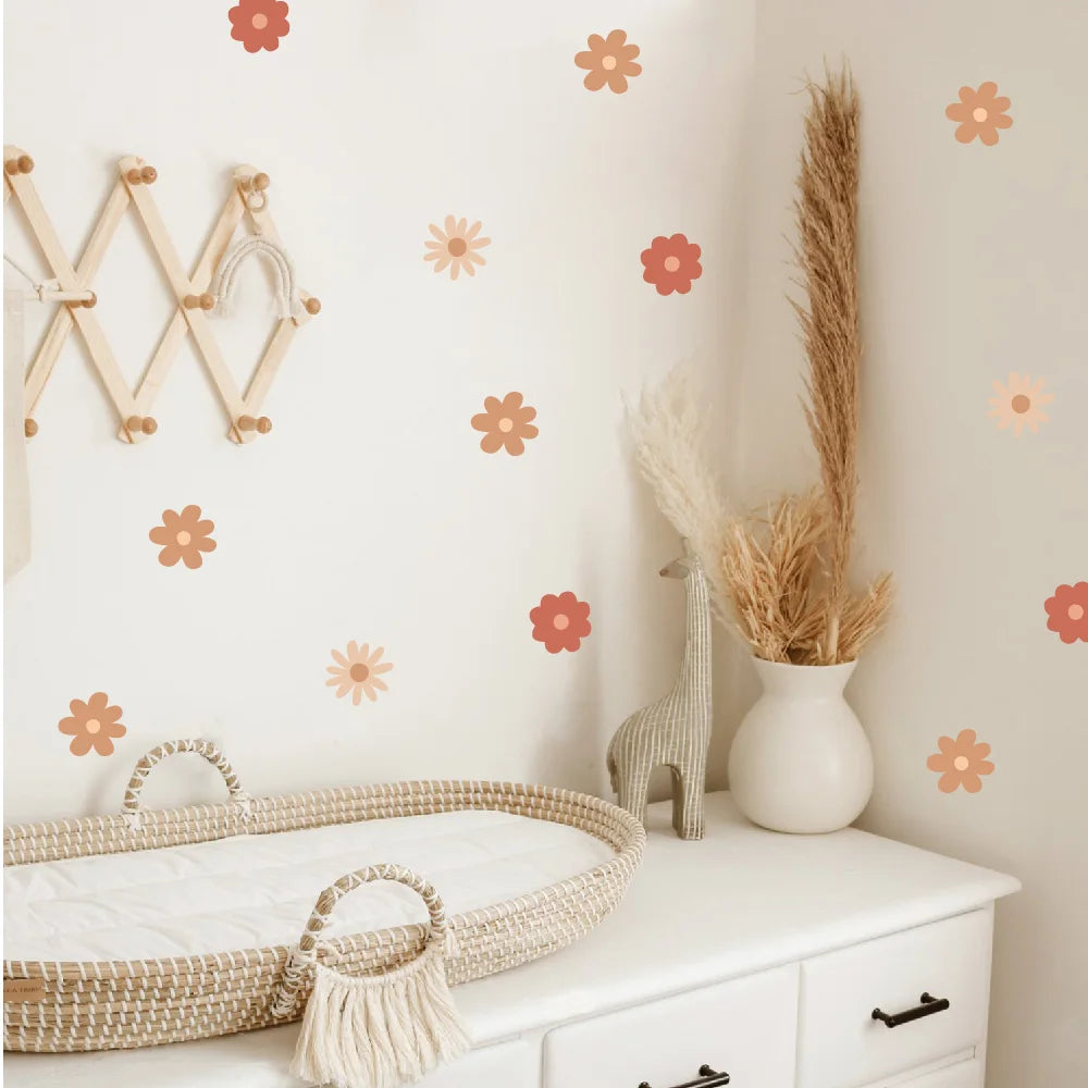 Nursery room with white dresser, decorative baskets, and floral wall decals.