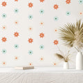 Wall with Pumkins colorful flower decals and a vase with dried plants on a white surface.