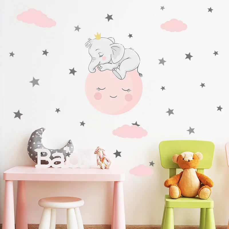 Children's room with wall decals of an elephant, moon, and stars, a pink table, green chair, and teddy bear.
