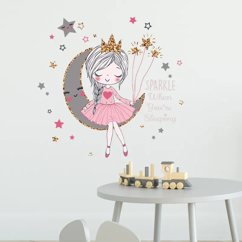 Wall decal of a fairy on a moon with decorative elements on a wall above a table with toys.