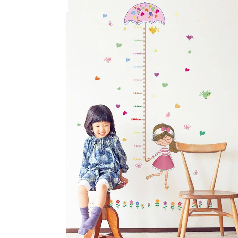 Child sitting on a chair next to a Tipi Tipi Tap Girl's Umbrella Height Chart wall decal.
