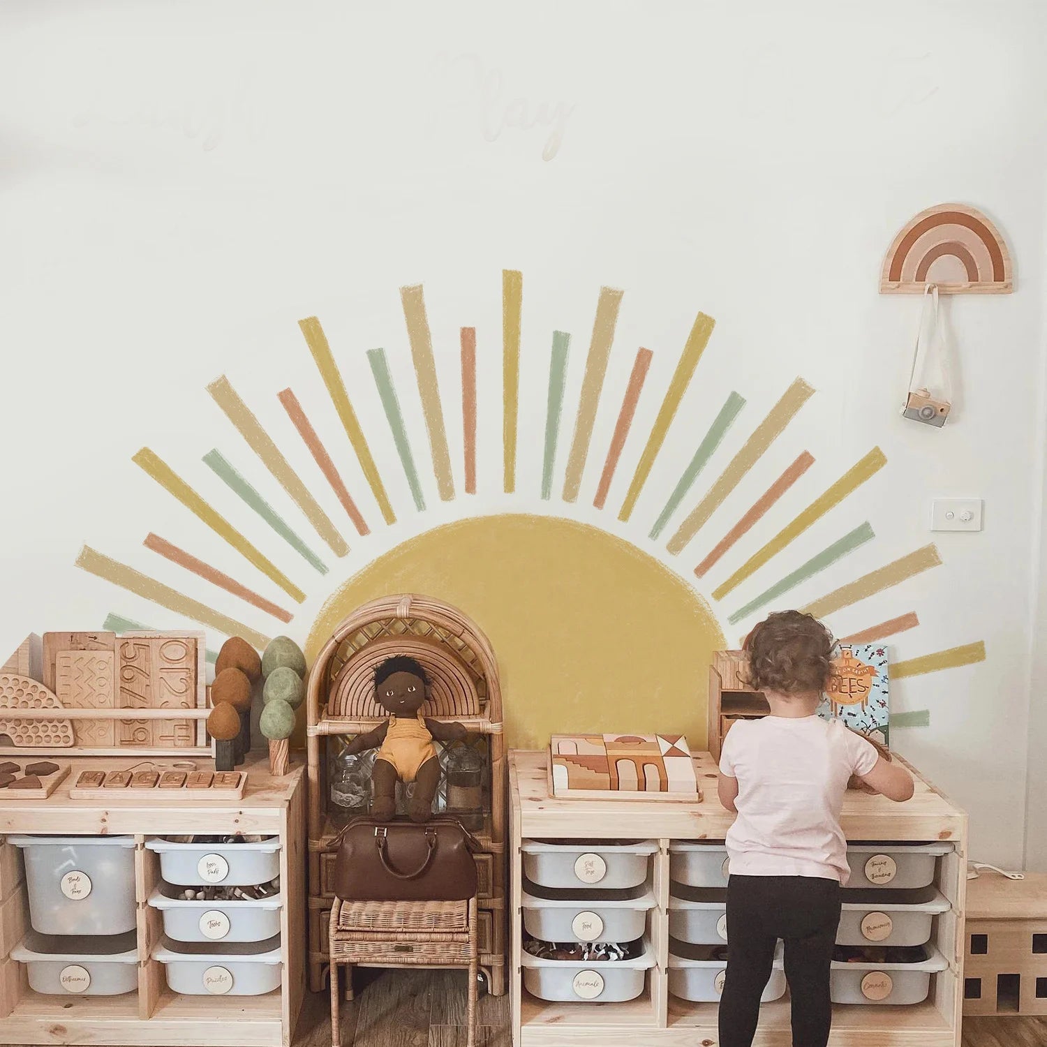 Child playing with a toy kitchen set in a room with Tipi Tipi Tap Sunburst Half Sun wall decal on the wall.