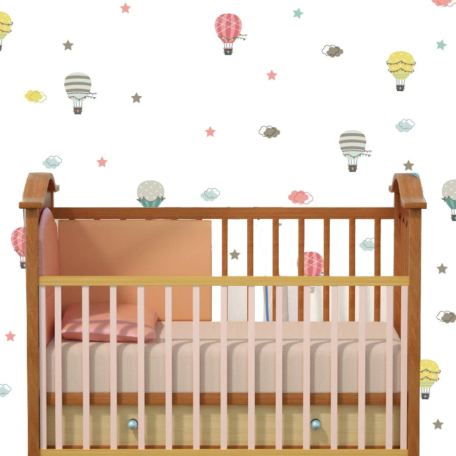 Wooden crib with pink blanket against a wall with colorful Tipi Tipi Tap Hot Air Balloon & Cloud wall decals.
