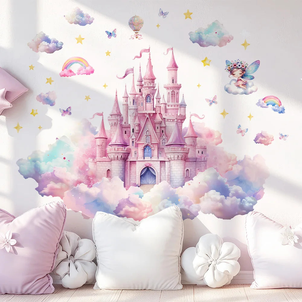 A pastel fairy-tale Tipi Tipi Tap Princess Castle Wall Decals featuring a pink castle surrounded by soft clouds, rainbows, stars, and small butterflies, shown on a bedroom wall above pillows and a light wood floor.