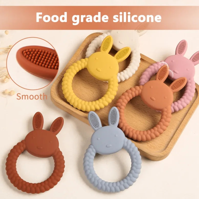 Set of colorful Tipi Tipi Tap Rabbit Silicone Baby Teether on a wooden tray with 'Food grade silicone' text above.
