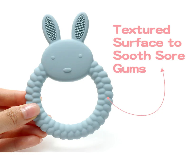 Blue Tipi Tipi Tap Rabbit Silicone Baby Teether held by a hand with text "Textured Surface to Sooth Sore Gums" on a white background