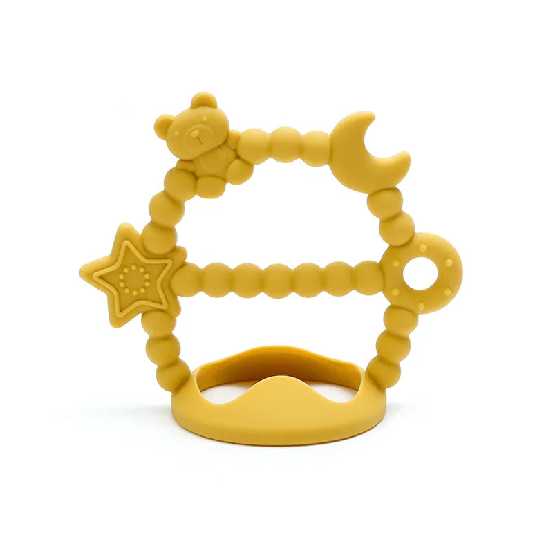 Golden color Tipi Tipi Tap silicone wrist teether with star, moon and bear shapes on a white background