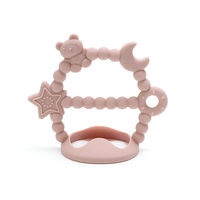 Pink Tipi Tipi Tap silicone wrist teether with star, moon and bear shapes on a white background