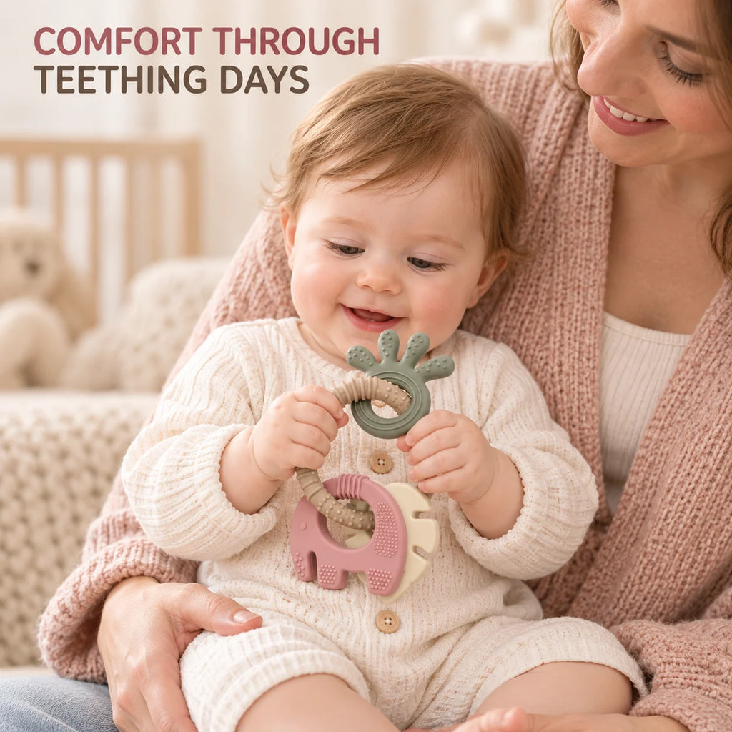 A baby wearing a cream knit romper sits on a mother's lap, holding a Tipi Tipi Tap 4-in-1 Silicone Baby Teether Ring Set. The teether features a sage green leaf-shaped ring and a pink elephant-shaped piece with a beige rope.