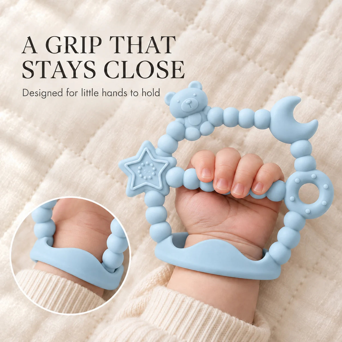 A light blue Tipi Tipi Tap Silicone Baby Wrist Teether (Moon & Star) with a bear, moon, star, and ring-shaped bead details, shown being held by a baby's hand on a cream quilted blanket. Text on the left reads 'A GRIP THAT STAYS CLOSE' and 'Designed for little hands to hold', with a circular inset showing the product worn on a wrist.
