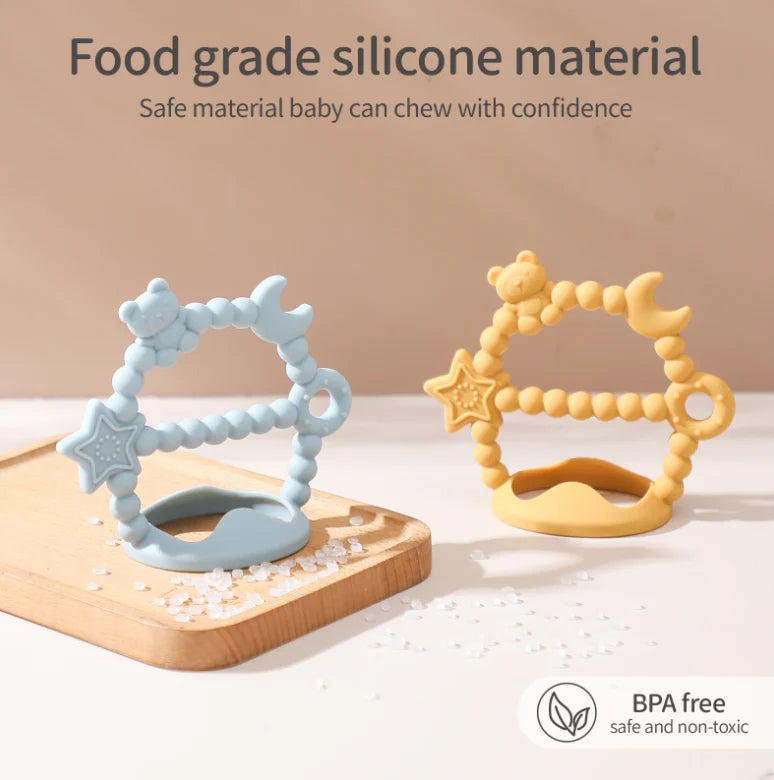 Two Tipi Tipi Tap silicone baby Wrist teether toys on a wooden surface with a beige background.