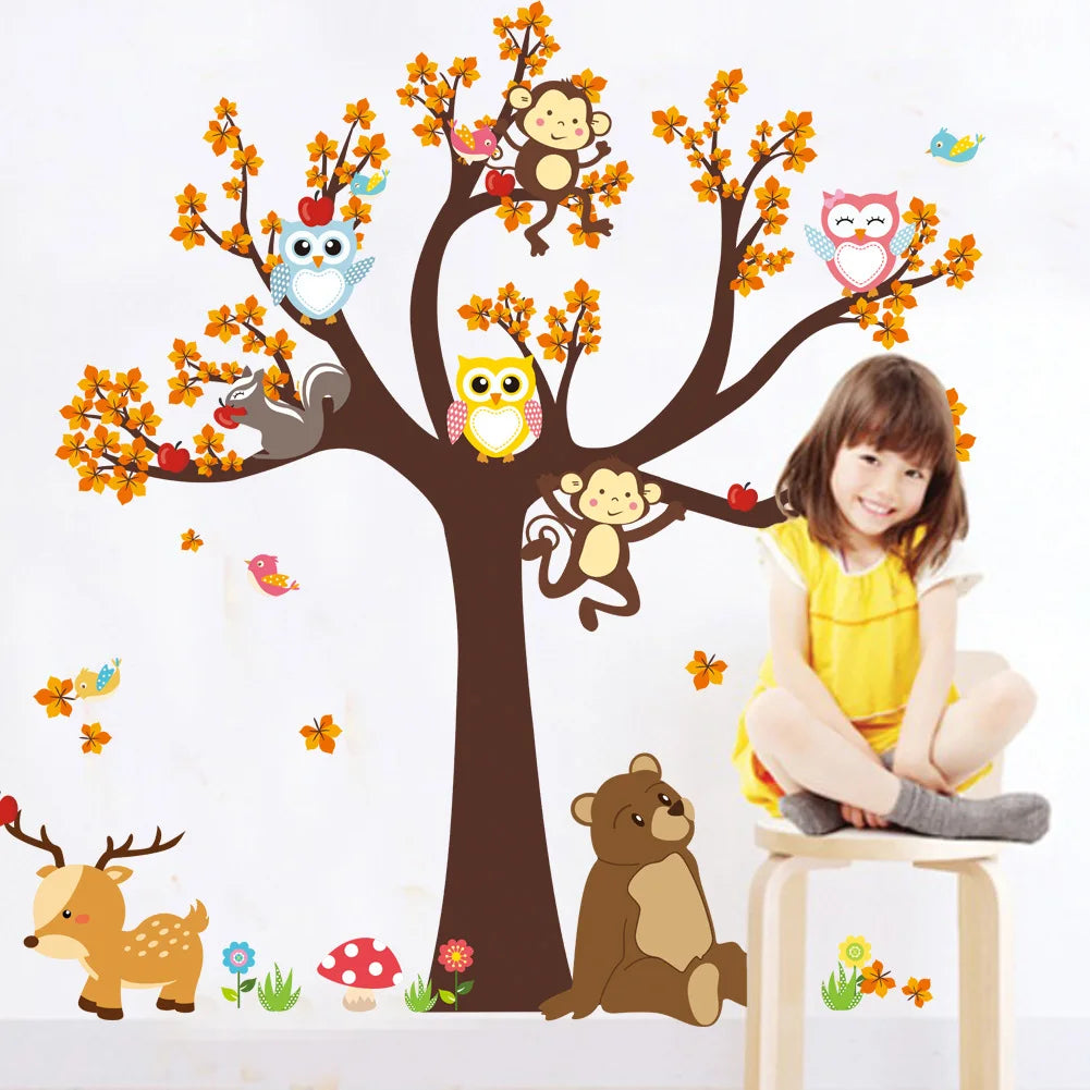 Child sitting in front of a wall with colorful animal decals including a tree, monkeys, owls, and a bear.